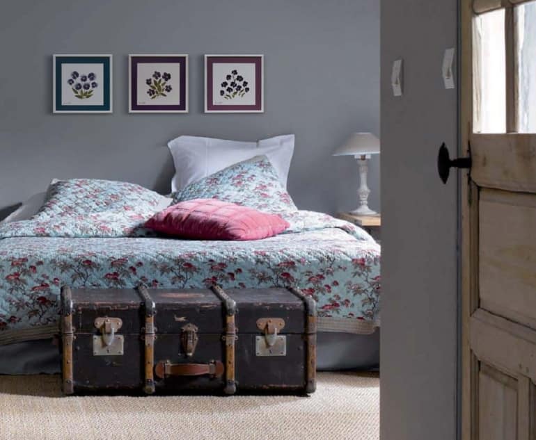Старый чемодан и гербарии в интерьере спальни напоминают о приятном путешествии